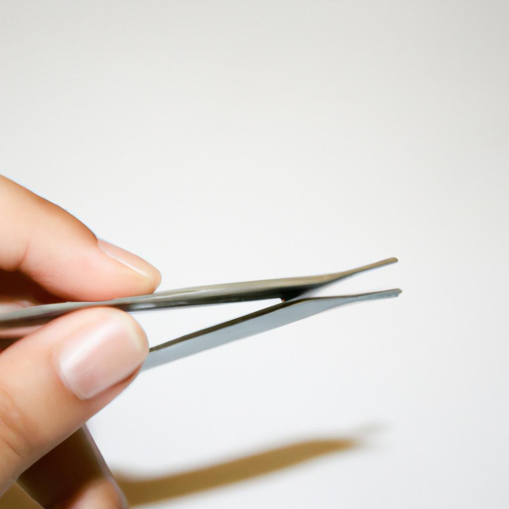 Person holding tweezers, demonstrating use